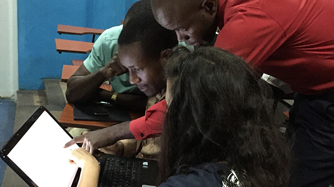 People gathered around a computer monitor