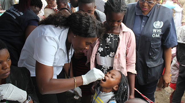 Photo of a health worker administering medicine to a child.